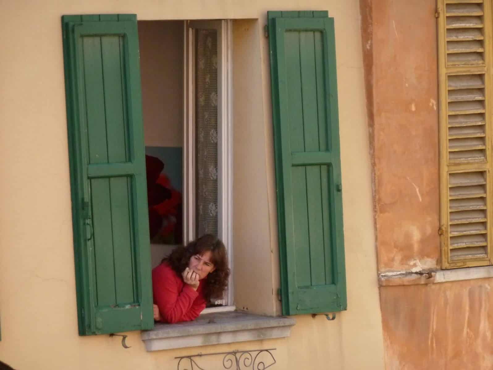 A local woman looks out her window from a home in the historic center